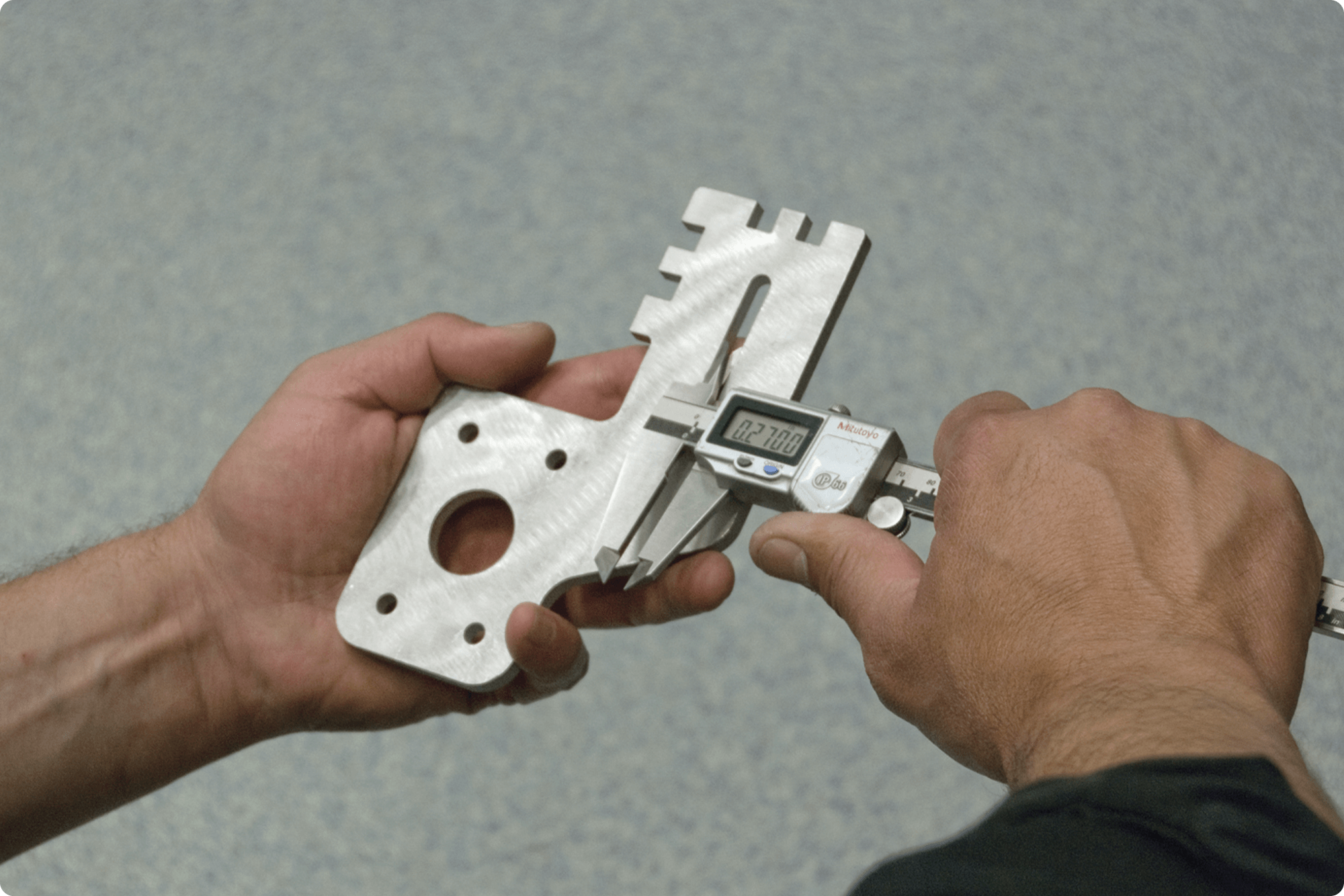 person doing an accuracy check on a metal cut part