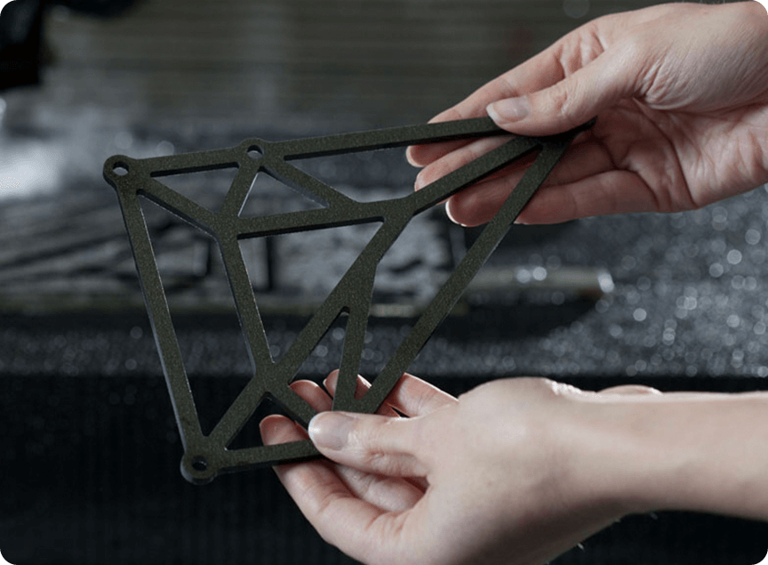 hands holding an intricately cut polygonal cut part with additional polygons cut into the center